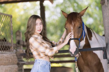 Çiftlik arazisinde poz veren güzel bir kovboy kız modeli. Aygırla ilgilenen güzel bir kız. Dişi ve güzel bir at. Arkadaşlık ve aşk kavramları.