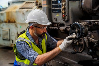 Personel ya da teknisyenler eski makinenin işleyişini uzaktan kontrol ediyorlar. Güvenlik kasklı bir işçi çelik makinesinde çalışıyor..