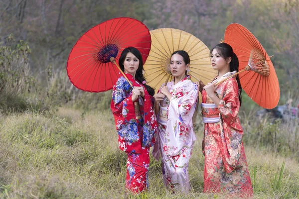 Kız nereye gidecek? Kimono ve sakura çiçekleri giyen çekici Asyalı kadın. Yanlara bakan Asyalı güzellik uzmanı kadın..