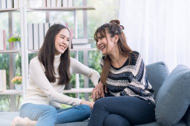 Evdeki oturma odasında gülen lezbiyen çift. Beyaz tenli aşıklar evlerinde kaynaşıyor, kanepede dinleniyorlar oturma odasında..