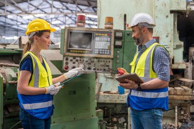 Genç adam ve genç kadın sanayi tesislerinde çalışıyorlar. Foreman, makinenin nasıl çalıştığını görmek için tahtayı eline al..