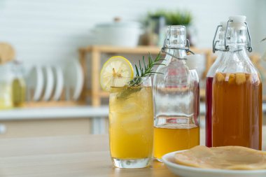 Limonlu kombu çayı ve mutfak arka planında cam sürahi doldurulmuş kök. Doğal kombu çayı mayalanmış çay sağlıklı organik içecekler bardakta..