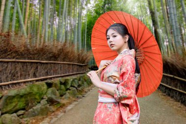 Kimmono elbiseli bir kadın Japonya 'da bir bambu korusunda şemsiye tutuyor. Japonya 'da önemli turistik merkezler