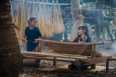 Two Asian girl is weaving the mat. girl weaving mats in the countryside. nong khai, thailand.