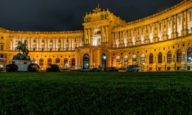 Viyana, Avusturya - 06 Ekim 2021: Viyana 'daki Hapsburg İmparatorluk Sarayı' nın görkemli cephesi. Barok binası, gece lambasıyla aydınlatılmış.