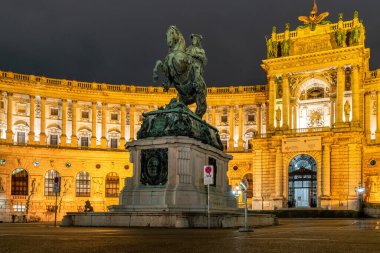 Viyana, Avusturya - 06 Ekim 2021: Viyana 'daki Hapsburg İmparatorluk Sarayı' nın görkemli cephesi. Barok binası, gece lambasıyla aydınlatılmış.