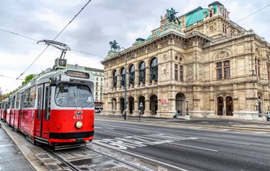 Viyana, Avusturya - 06 Ekim 2021: Viyana Operası ve eski geleneksel kırmızı tramvayın heybetli ve lüks kemerli perisi. Avusturya 'nın popüler turistik merkezi. Antik barok mimarisi