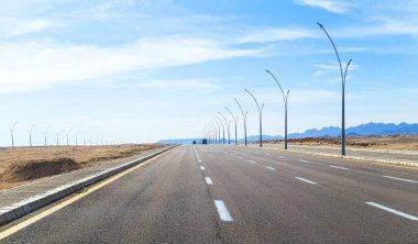 Çölün ortasındaki modern otoyol ve Orta Doğu 'daki dağlar.