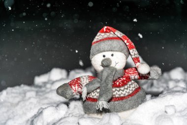 Oyuncak kardan adam, karanlık bir Noel gecesinin arka planında, gökyüzü ve kar.