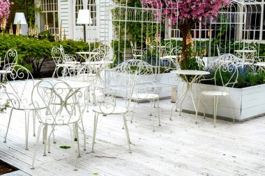 Demirden mobilyaları olan güneşli bir açık kafe.