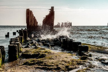 Old ruined wooden pier and a sandy beach