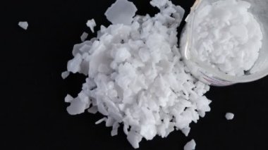 Siyah arka planda potasyum hidroksit tanecikleri, laboratuvarda kimya.