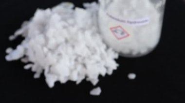 Siyah arka planda potasyum hidroksit tanecikleri, laboratuvarda kimya.