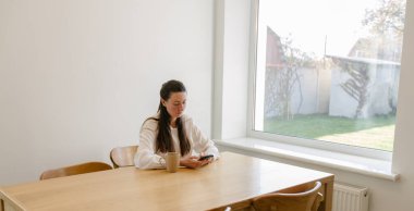 Oturma odasında telefon kullanan bir kadın.