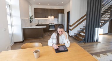 Oturma odasında telefon kullanan bir kadın. Modern oturma odası İskandinav minimalist tarzında.