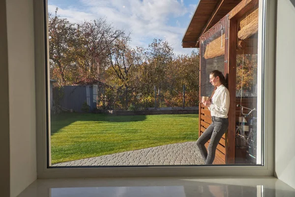 Frau Entspannt Sich Ihrem Hinterhof Neben Einem Fenster Beim Kaffeetrinken — Stockfoto