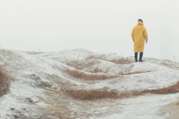 Man lost on a white stalker mountain in fog wearing yellow raincoat