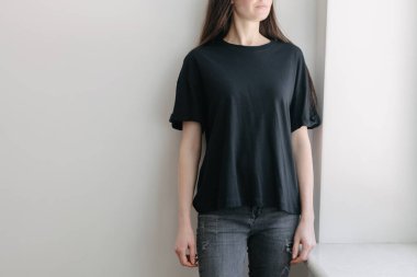 Logonuz için yeri olan siyah, boş tişört giyen bir kadın. Kapalı mekanda modellik veya tasarım yapın.