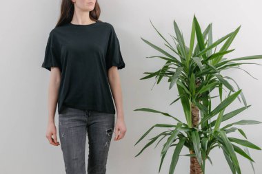 Logonuz için yeri olan siyah, boş tişört giyen bir kadın. Kapalı mekanda modellik veya tasarım yapın.