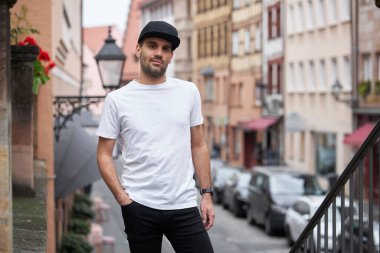 Hippi gibi yakışıklı bir erkek modelin üzerinde beyaz boş tişört. Logonuz ya da gelişigüzel tasarlanmış bir şehir tarzı.