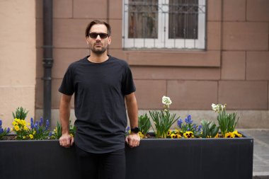 Hippi gibi yakışıklı bir erkek modelin üzerinde siyah boş tişört. Logo ya da şehir tarzı tasarım için yeri var.