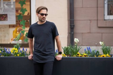 Hippi gibi yakışıklı bir erkek modelin üzerinde siyah boş tişört. Logo ya da şehir tarzı tasarım için yeri var.