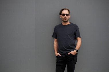 Hippi gibi yakışıklı bir erkek modelin üzerinde siyah boş tişört. Logo ya da şehir tarzı tasarım için yeri var.