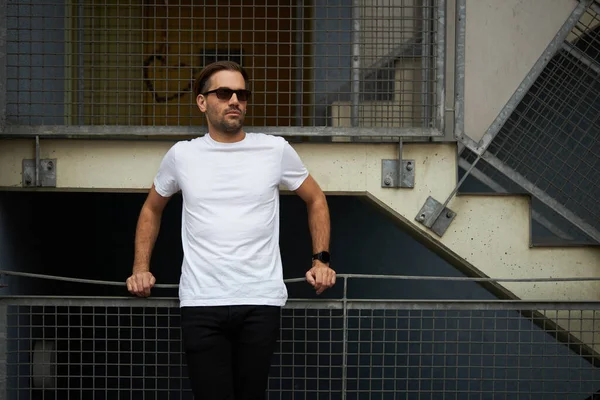 Hippi gibi yakışıklı bir erkek modelin üzerinde beyaz boş tişört. Logonuz ya da gelişigüzel tasarlanmış bir şehir tarzı.