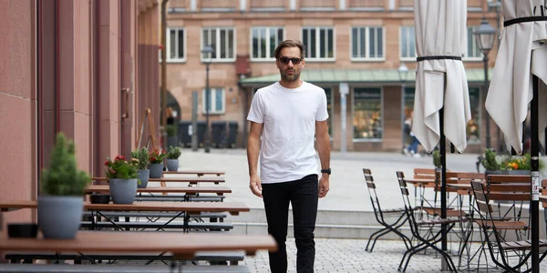 Hippi gibi yakışıklı bir erkek modelin üzerinde beyaz boş tişört. Logonuz ya da gelişigüzel tasarlanmış bir şehir tarzı.