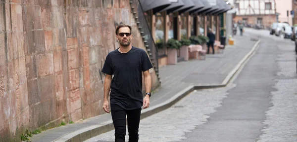 Hippi gibi yakışıklı bir erkek modelin üzerinde siyah boş tişört. Logo ya da şehir tarzı tasarım için yeri var.