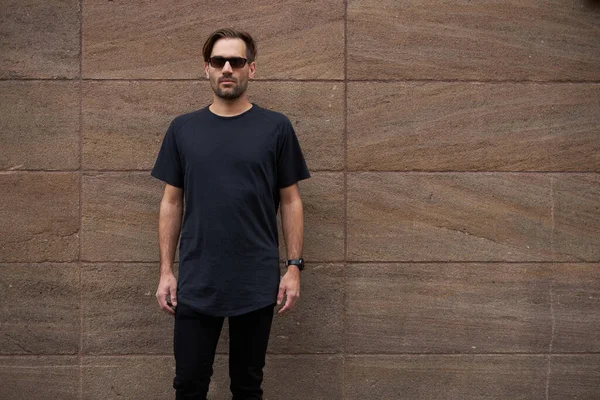 Hippi gibi yakışıklı bir erkek modelin üzerinde siyah boş tişört. Logo ya da şehir tarzı tasarım için yeri var.