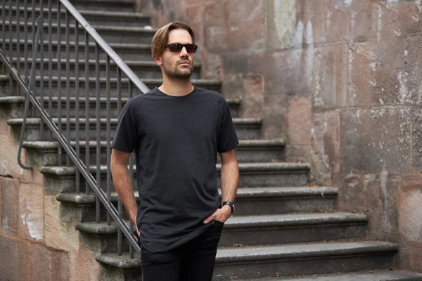 Hippi gibi yakışıklı bir erkek modelin üzerinde siyah boş tişört. Logo ya da şehir tarzı tasarım için yeri var.