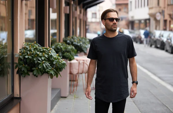 Hippi gibi yakışıklı bir erkek modelin üzerinde siyah boş tişört. Logo ya da şehir tarzı tasarım için yeri var.