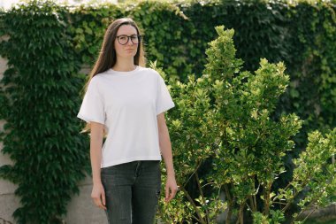 Woman wearing white t-shirt with space for logo or design in the park in summer