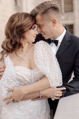 Genç çift gelin ve damat, şehrin arka planında birbirlerine nazikçe bakıyorlar. Düğün günü kavramı. 