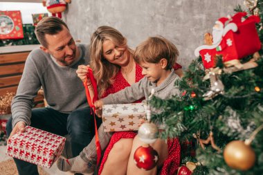 Baba, anne ve oğlunun fotoğrafı. Zaman geçirmek. Evdeki Noel ağacının mutlu anları vardır. Tatile hazırlanıyorum. Tek çocuklu bir aile. Mutluluk. Eğlenmene bak. kırmızı yeşil decore