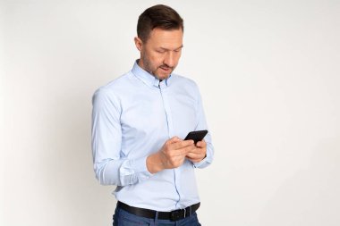  Açık tişörtlü şık iş adamı akıllı telefon kullanıyor, arka planda stüdyo resmi var.. 