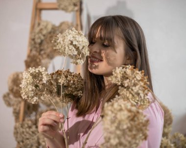 Kurumuş, dengeli ortanca buketi, ve genç, koyu saçlı kızın ellerinde, çiçekçi, mutlu yüzünde çiçeklerin gölgeleri. Yüksek kalite fotoğraf