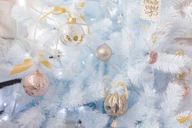 Gümüş sarısı Noel toplarıyla süslenmiş beyaz Noel ağacı ve ışıl ışıl parlayan parlak cam toplar ve beyaz mavi bir dal, dekoratif ışıklar, kopyalama alanı. Fotoğraf.