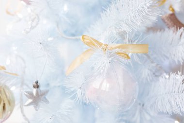 Gümüş sarısı Noel toplarıyla süslenmiş beyaz Noel ağacı ve ışıl ışıl parlayan parlak cam toplar ve beyaz mavi bir dal, dekoratif ışıklar, kopyalama alanı. Fotoğraf.