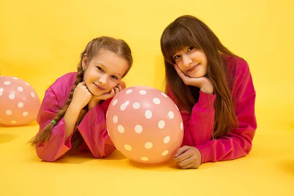 Dziewczęta Siostry Leżące Żółtym Tle Studio Patrząc Kamerę Uśmiechając Się — Zdjęcie stockowe