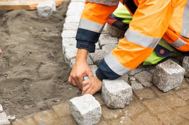 Kaldırım taşlarıyla asfalt döşeme işi. Elinde inşaat malzemeleri, beton ürünleri, yol ya da kaldırım inşaatı sanayisi olan tanınmayan kişi.