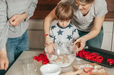 Tek çocuklu bir aile mutfakta yemek pişiriyor. 4 yaşındaki çocuk için aşçılık dersleri anne, baba ve oğul mutfakta birlikte yemek pişiriyorlar. Mutlu insanlar eğlenir.