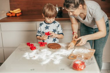 Anne ve oğlu pasta hazırlıyor, kurabiye mutfakta. Kadın oğluna yemek yapmayı öğretiyor, evdeki rahat mutfakta yemek yapmayı. Bekar bir anne. Mutlu saatler. Takım çalışması. Kadın ve çocuk.
