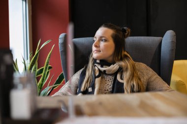 35 yıl boyunca kafe 'de oturan güzel bir kadın pencereye bakarak romantik melankolik bir ruh hali içinde kafeterya masasında rahat bir koltukta hayal kuruyor.