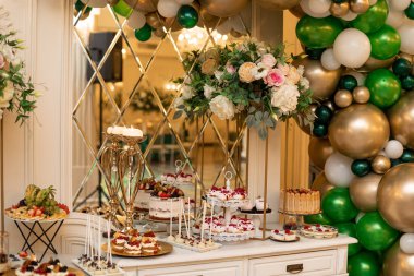 Düğün töreninde balonlarla süslenmiş ve çiçek aranjmanlarıyla süslenmiş tatlı bir büfe. Lezzetli bir düğün büfesi. Bayram etkinliği. Ziyafet ve düğün organizasyonu. Düğün çiçekçisi.. 