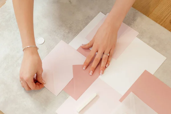 Przycięte zdjęcie kobiecych rąk robiących różowy skład chwasty koperta owijająca papier zaproszeniowy, wosk uszczelniający, papierniczy. — Zdjęcie stockowe