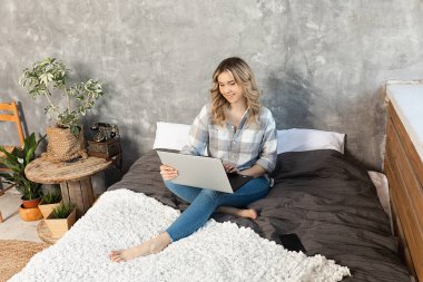 Dizlerinin üzerinde çalışan sarışın genç bir kadının portresi. Daire uzaktan çalışma için ev ofisi olarak kullanılır..