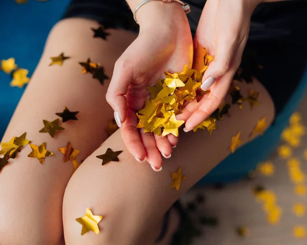 Обрезанный образ молодой женщины в платье. Голые ноги с золотой бумагой и фольгой звезды с гладкой светлой кожей. Праздничная вечеринка — стоковое фото