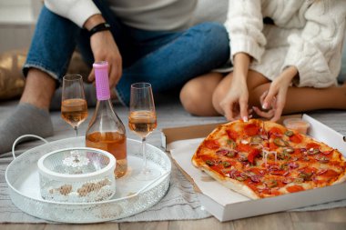 Birbirine aşık genç bir çift lezzetli pizza yemek ve şarap içmek için odadaki örgü örülmüş battaniyeye yerleşti. Romantik öğle yemeği. Yaratıcı randevu. Hayatın harika anları. 